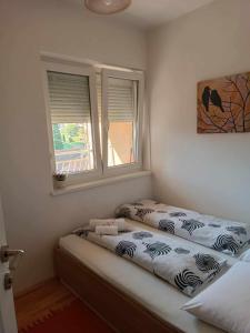 um quarto com uma cama com duas janelas e uma roupa de cama com espectáculos em Apartmani Dar Lux em Banja Koviljača