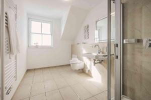 a white bathroom with a toilet and a sink at Ferienhäuser Baltic Lagoon Haus 14b in Fuhlendorf +25 photos