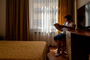 a woman reading a book in a hotel room at Primavera 2 Hotel in Pazardzhik