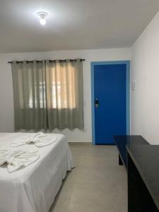 a bedroom with a bed and a blue door at Suite Grega 5- Centro da Vila Abrãao in Abraão