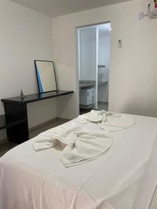 uma cama branca num quarto branco com um espelho em Suite Grega 5- Centro da Vila Abrãao em Abraão