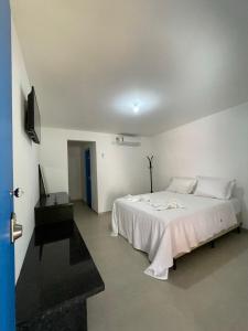 a white bedroom with a bed and a desk at Suite Grega 5- Centro da Vila Abrãao in Abraão