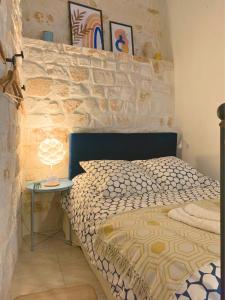 a bedroom with a bed and a table with a lamp at La Casita - Studio Confort avec Climatisation - Charme de l'ancien - Hypercentre Uzès, Pont du Gard in Uzès
