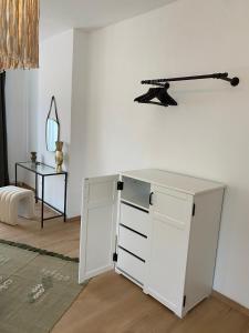 - une commode blanche dans une pièce avec un miroir dans l'établissement Cosy Alba plein centre Visé, à Visé