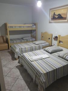 three beds are lined up in a room at Hotel Graunas in São Carlos