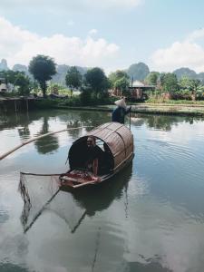 two people in a boat with a net in the water at Tam Coc Lotus Flower Homestay in Ninh Binh