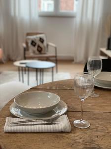 - une table en bois avec une assiette et deux verres à vin dans l'établissement Cosy Alba plein centre Visé, à Visé