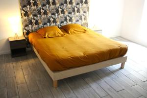 uma cama com um edredão amarelo e duas almofadas em Ti Guernevez em Briec