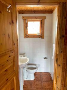 La salle de bains est pourvue de toilettes, d'un lavabo et d'une fenêtre. dans l'établissement Chalé do Sossego Serra da Estrela, à Cortes do Meio