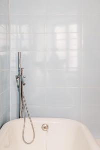 a white tub in a bathroom with white tiles at La Maison de Laulie in Bagnères-de-Bigorre