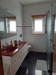 ein Bad mit einem roten Waschbecken und einer Dusche in der Unterkunft Merci Beach House in Carvoeira