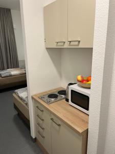 a kitchen with a microwave and a bowl of fruit on a counter at Longhouse Aparthotel in Dreieich