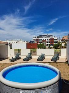 una gran piscina azul con sillas y edificios en Merci Beach House, en Carvoeira