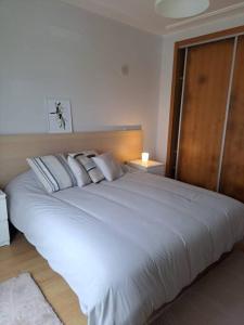 1 dormitorio con 1 cama blanca grande con almohadas en Merci Beach House, en Carvoeira