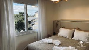 a bedroom with a bed with towels on it at Apartamento Novo Aconchegante e Moderno em Canela in Canela