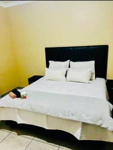 un grande letto con testiera nera e cuscini bianchi di Executive Guesthouse a Vereeniging