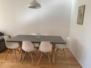 comedor con mesa negra y sillas blancas en Appartement cosy, en Lyon