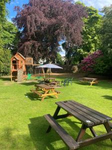 a group of picnic tables and an umbrella in a park at Bennachie Lodge Hotel in Kemnay in Inverurie