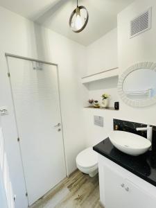 Baño blanco con aseo y lavamanos en Apartament CHIC, en Vatra Dornei