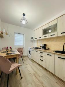 cocina con armarios blancos, mesa y sillas en Apartament CHIC, en Vatra Dornei