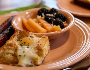 a plate with a piece of bread and a bowl of fruit at LakePlace Bed & Breakfast in Dresser +6 photos
