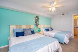a bedroom with two beds and a ceiling fan at Crescent Shores North - 1302 in Myrtle Beach +23 photos