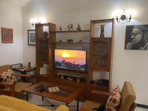 a living room with a flat screen tv and wooden shelves at Beach Townhouse - Murdeira Village in Beirona