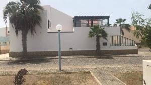 una casa blanca con palmeras delante en Beach Townhouse - Murdeira Village en Beirona