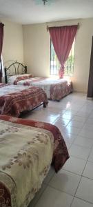 a room with three beds and a window at HOTEL MONTALVO in Tezontepec de Aldama