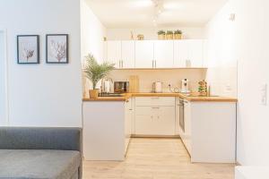 una cocina con armarios blancos y un sofá en una habitación en Apartment Leverkusen en Leverkusen