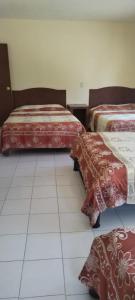 a room with two beds sitting on a tiled floor at HOTEL MONTALVO in Tezontepec de Aldama