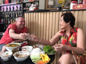 a man and a woman sitting at a table with food at The Vinyl Homestay in Ho Chi Minh City