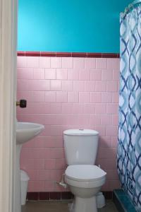 a pink tiled bathroom with a toilet and a sink at La Palmera Hostel in Cali