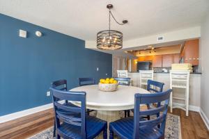 a dining room with a white table and blue chairs at Bahama Sands - 704 in Myrtle Beach