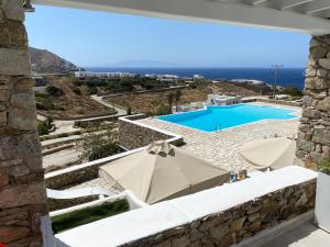 a patio with an umbrella and a swimming pool at Rineia Complex by Live&Travel in Mýkonos City