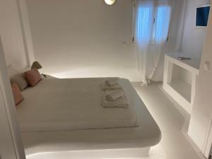 ein weißes Schlafzimmer mit einem Bett mit Handtüchern darauf in der Unterkunft Rineia Complex by Live&Travel in Mykonos Stadt