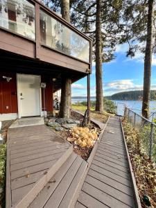 uma casa com um deque de madeira junto à água em The Starboard Side Room - Cliffside, Ocean Views em Kodiak