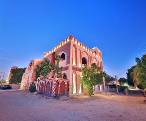 um grande edifício com uma árvore em frente em El Hanna Valley View em Luxor