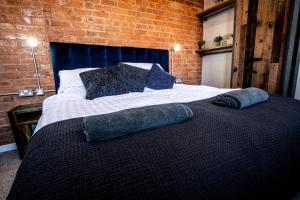 ein Schlafzimmer mit einem Bett mit zwei Kissen darauf in der Unterkunft VIP 3BR Grade2 Luxurious Industrial House with WOOD FIRE, Electric blinds and big Cast iron Windows in the heart of the JQ in Birmingham