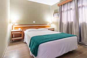 a bedroom with a large bed with a green blanket at Braston Augusta Hotel by Castelo Itaipava in Sao Paulo