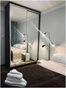 a mirror in a bedroom with a bed and two lamps at Apartament Zdrojowy in Busko-Zdrój