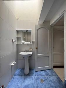 Baño blanco con lavabo y puerta en Casa vacacional ideal para familias / Los Reyes, en Loja