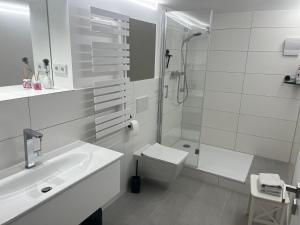 a white bathroom with a sink and a shower at Anderswo Bad Aibling in Bad Aibling