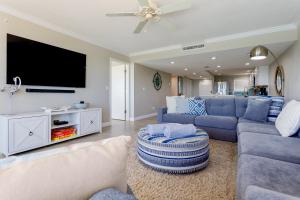 uma sala de estar com mobiliário azul e uma televisão de ecrã plano em Paloma Penthouse em Ormond Beach