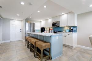 a kitchen with white cabinets and bar stools at Paloma Penthouse in Ormond Beach