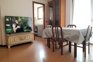 comedor con mesa, TV, mesa y sillas en Verona Est Due, en San Martino Buon Albergo