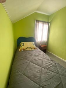 um quarto com uma cama numa sala verde em Calor y amor de hogar chilote em Castro