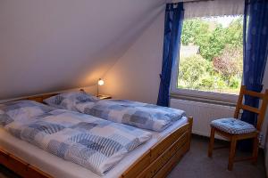 a bedroom with a bed with a window and a chair at Ferienwohnung Schwudke Wohnung 62 in Gartow