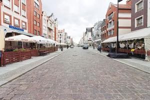 uma rua de calçada com mesas e guarda-sóis numa cidade em Amore Mio Stare Miasto Apartamenty em Elblag