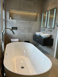 a white tub in a bathroom with two sinks at Luxury detached 4-bedroom villa with free parking in Cockfosters